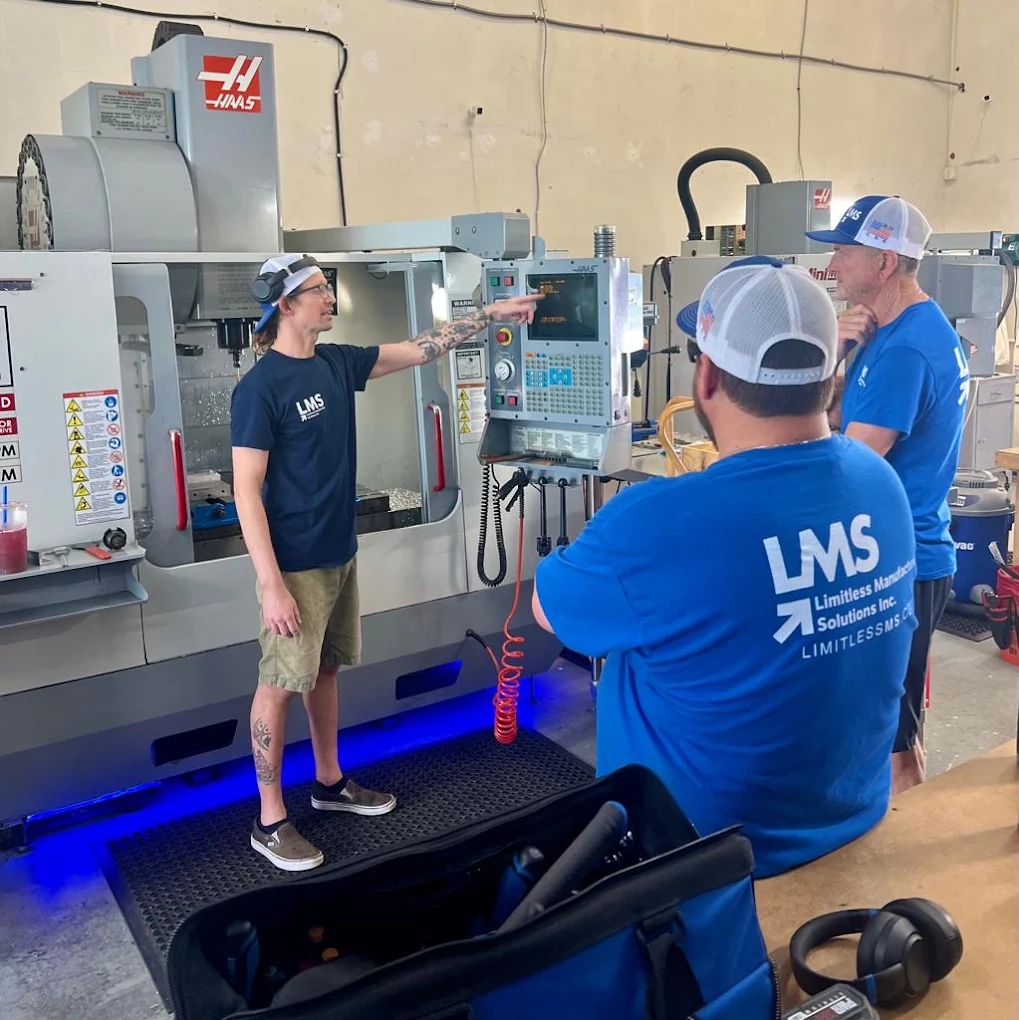Manufacturing technicians reviewing a CNC machine control panel on the shop floor