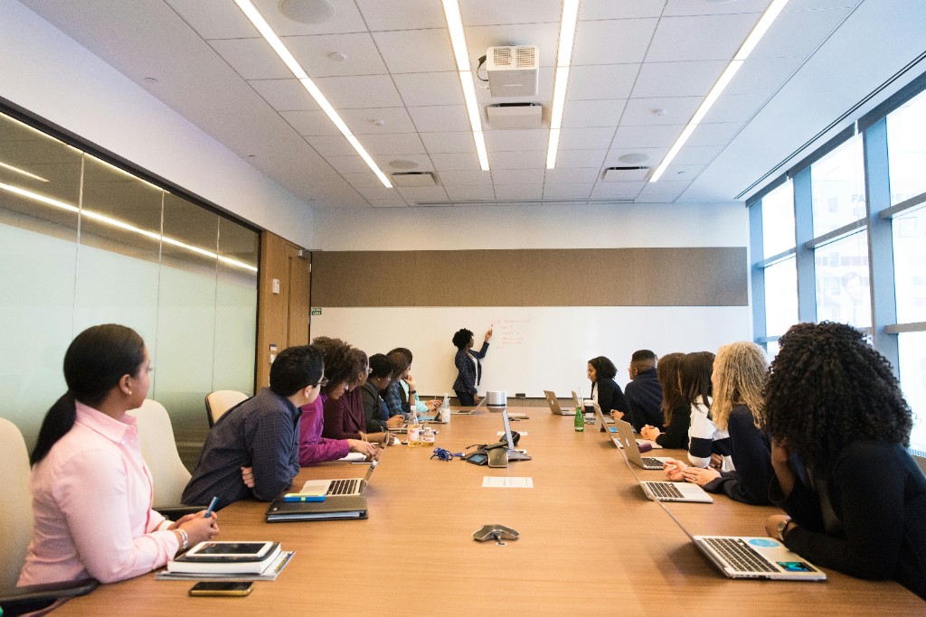 Diverse professionals in a modern conference room during a collaborative meeting and whiteboard presentation